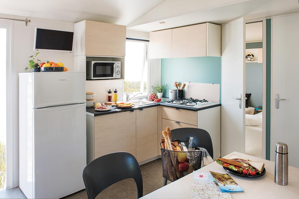 Cuisine équipée de mobil home du camping les 7 saints à Erdeven avec une table et des chaises